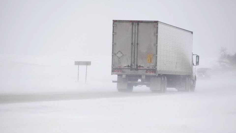 A photo of cargo struck driving through misty snow on a road in winter.