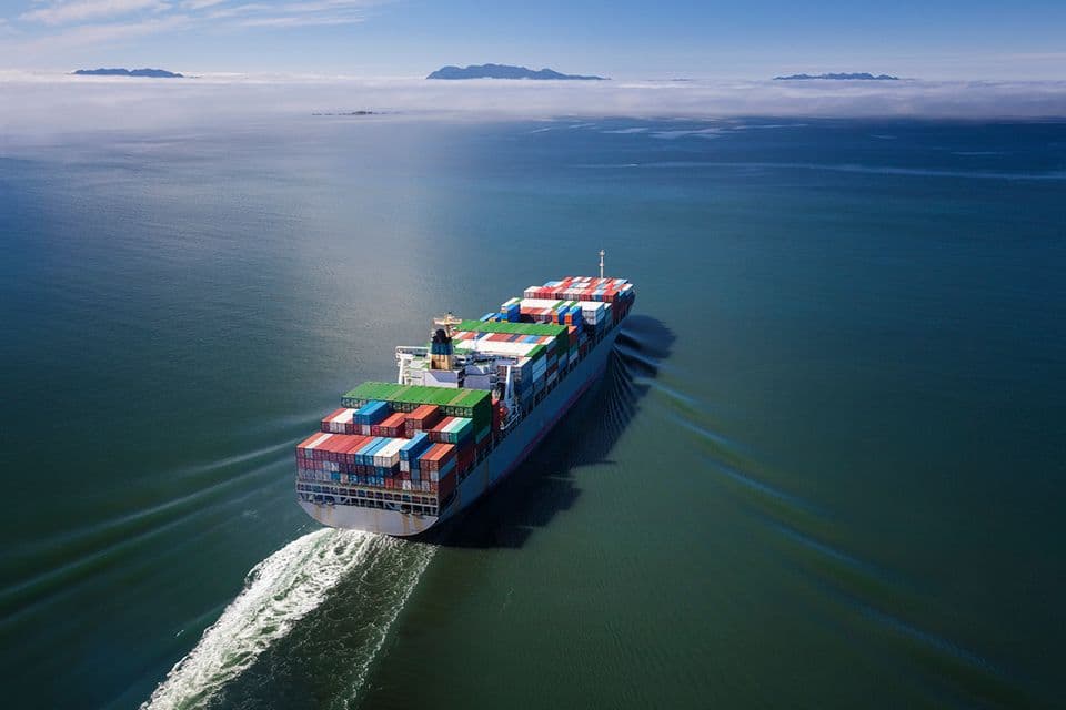 A photo from above of a marine cargo ship in the sea, with many different colour shipping containers on it