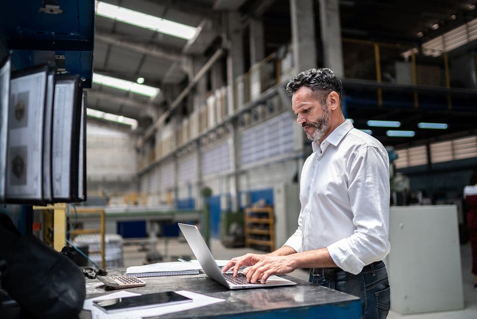 Man working on laptop in a warehouse