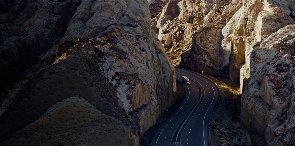 A photograph of a cargo truck driving through a dramatic rocky landscape