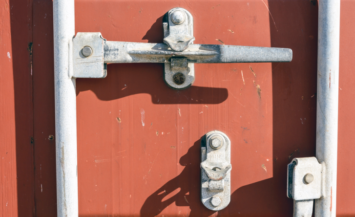 A close-up of the white locking mechanism on a red shipping container.