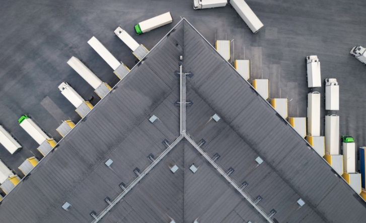 A view from above of a truck depot, some of the cargo trucks are leaving while others are parked