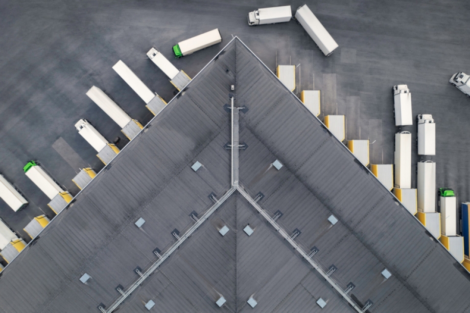 A view from above of a truck depot, some of the cargo trucks are leaving while others are parked