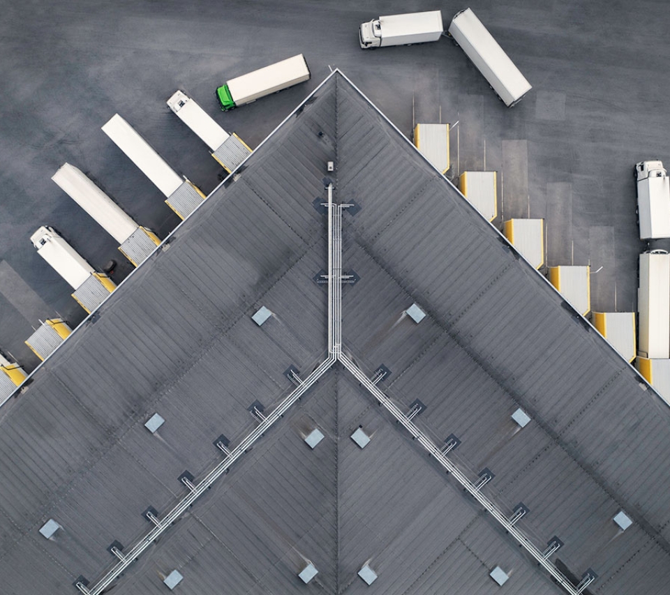 A view from above of a truck depot, some of the cargo trucks are leaving while others are parked