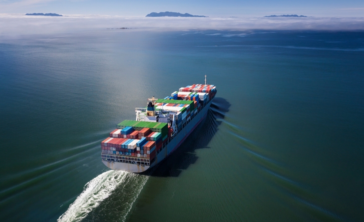 A photo from above of a marine cargo ship in the sea, with many different colour shipping containers on it