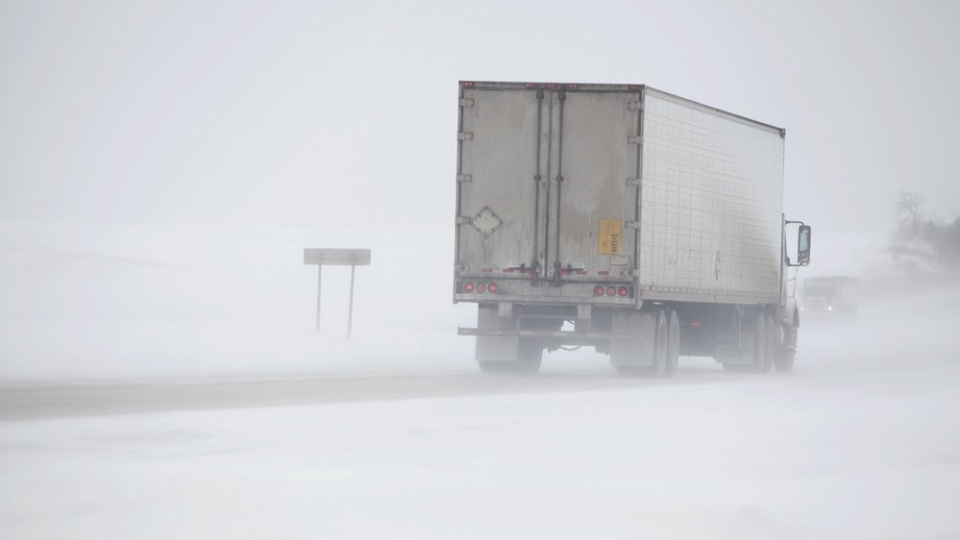 A photo of cargo struck driving through misty snow on a road in winter.